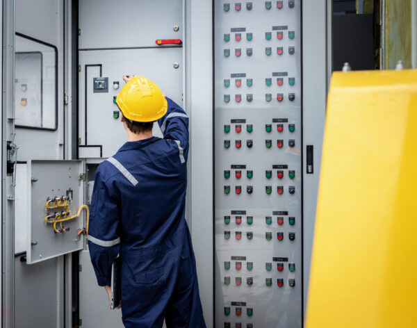 Electrical engineer working in control room. Electrical engineer man checking Power Distribution Cabinet in the control room